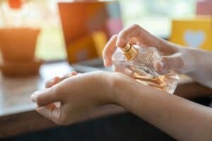 A lady spraying perfume on her wrist to make it last longer.